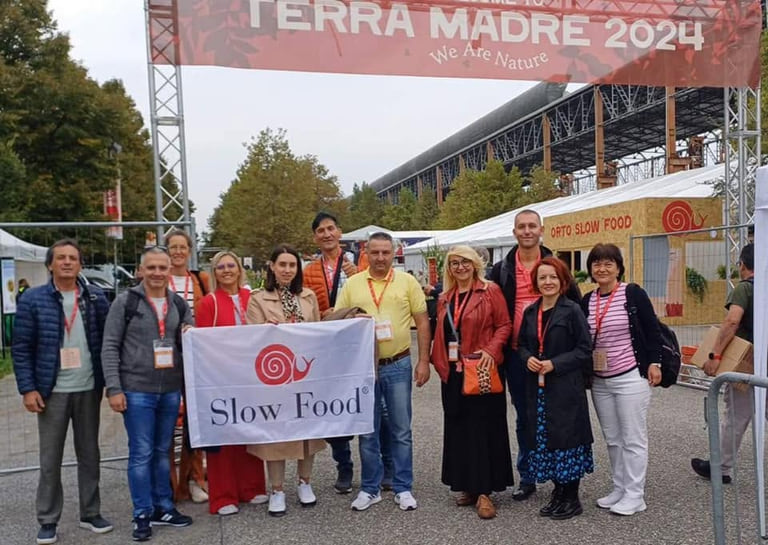 Дел од македонската делегација стои под ознаката Terra Madre 2024 и држи знаме на Slow Food.